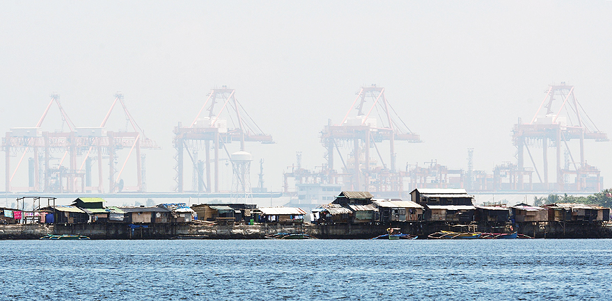 A row of shanty dwellings are dwarfed by giant cranes at the south harbour cargo terminal in Manila on July 13, 2016. 
The Philippines' economy grew a better-than-expected 6.9 percent in the first quarter, the government said May 19, putting it on track to meet full year targets and making it one of Asia's best performers for the three month period. / AFP PHOTO / TED ALJIBE