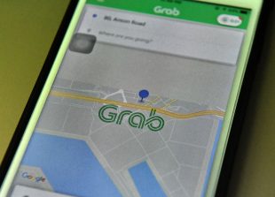 This photo illustration taken on March 26, 2018 shows the Grab booking application seen on a smart phone in Singapore. 
Singapore-based ride-hailing firm Grab announced on March 26 it has bought US rival Uber's business in Southeast Asia, ending a fierce battle for market share in the region. / AFP PHOTO / Roslan RAHMAN