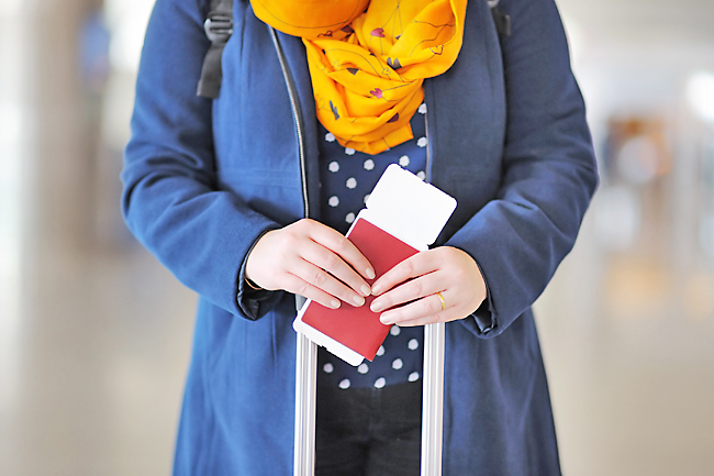 Close up photo of woman holding passport and boarding pass at the airport