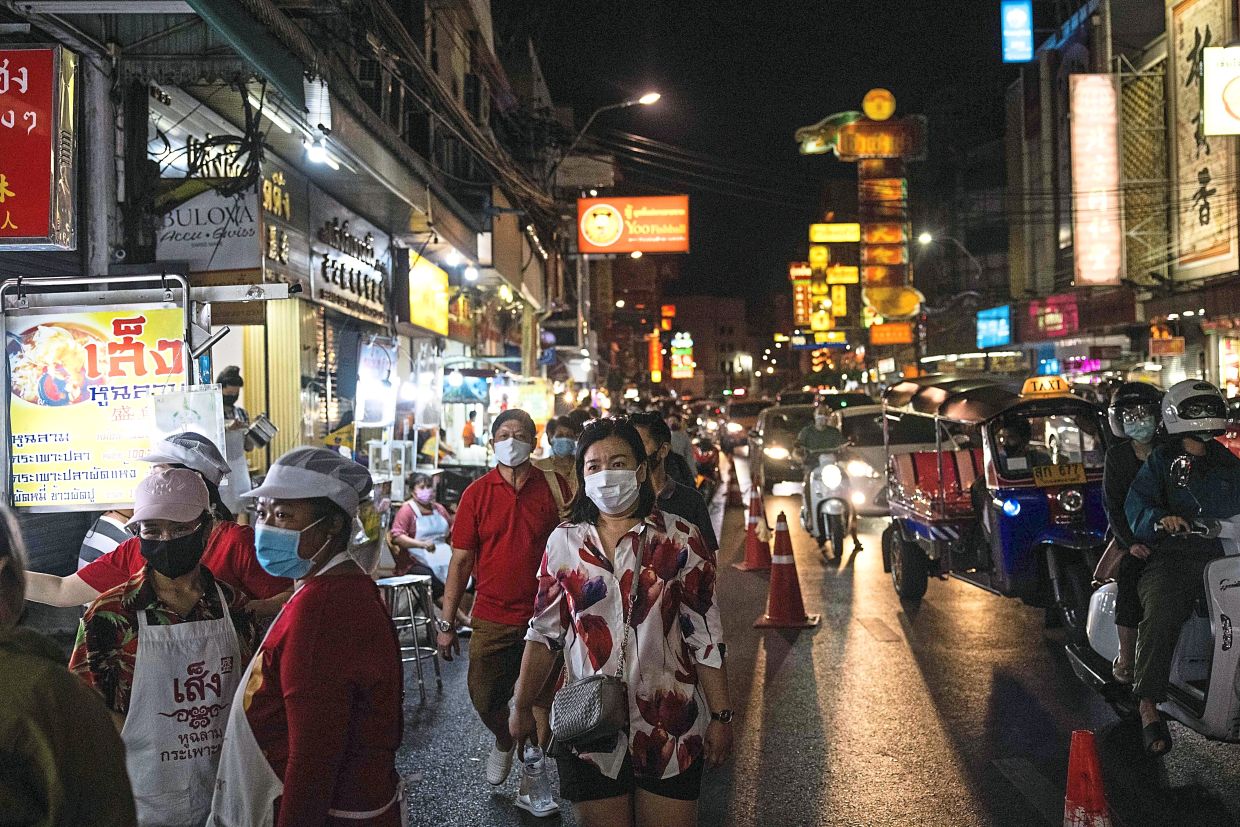 People wearing face masks walk through Chinatown in Bangkok on January 2, 2021, after the Thailand's capital imposed temporary lockdown measures aimed at curbing the rising coronavirus toll. (Photo by Jack TAYLOR / AFP)