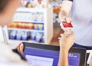 Cashier Accepts Card Payment From Customer In Delicatessen